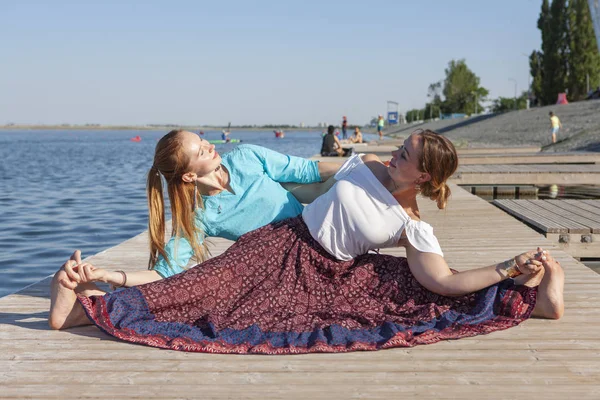 Две женщины занимаются в парке. Молодая красивая женщина делает упражнения вместе на открытом воздухе . — стоковое фото
