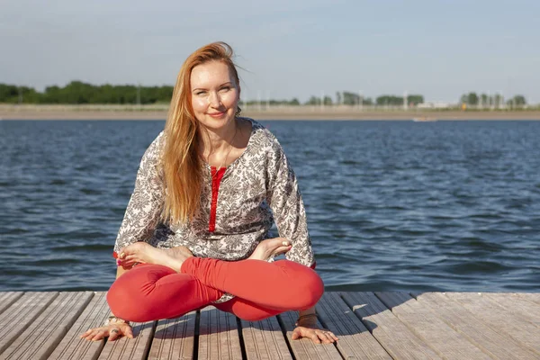 Una imagen de una mujer guapa haciendo yoga en el lago — Foto de Stock