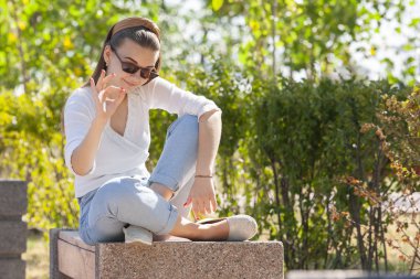 Parkta bankta oturan genç güzel kadın.