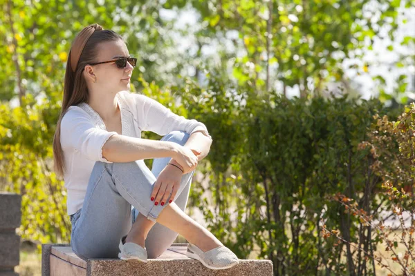 Joven hermosa mujer sentado en banco en parque . — Foto de Stock