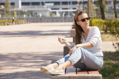 Parkta bankta oturan genç güzel kadın.