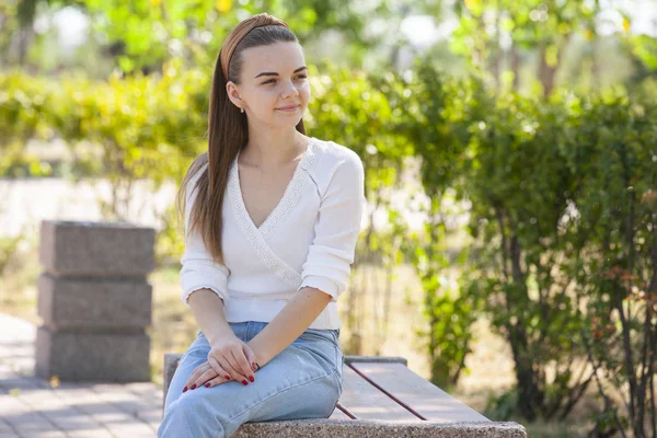 Joven hermosa mujer sentado en banco en parque . — Foto de Stock