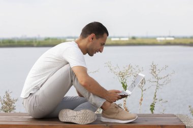 Ofis dışında dizüstü bilgisayar ile oturan genç adam