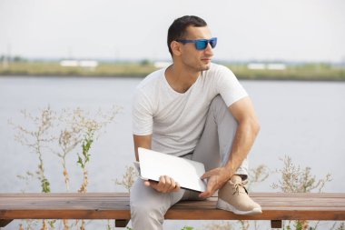 Ofis dışında dizüstü bilgisayar ile oturan genç adam