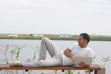 Ofis dışında dizüstü bilgisayar ile oturan genç adam