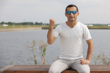 Gülen sakallı genç adam başparmak yukarı gösteren. Neşeli yakışıklı genç adam açık işaret.