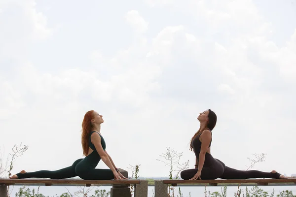 Zwei Frauen beim Yoga im Freien. Yogalehrer zeigt Posen — Stockfoto