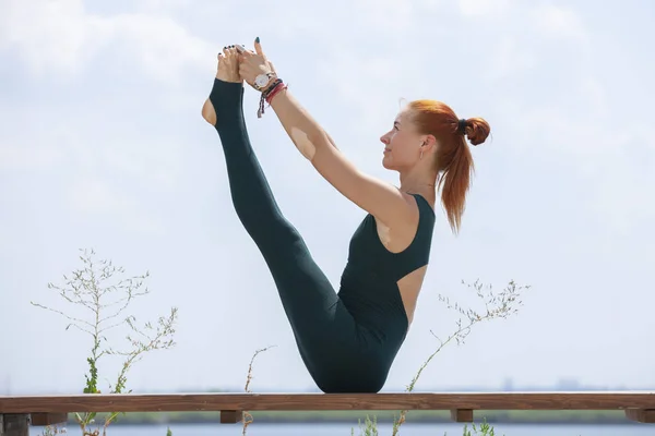 Picture of young fitness lady outdoors in the beach make yoga stretching exercises.