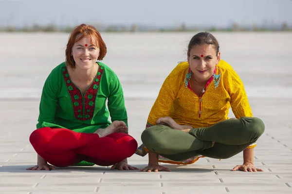 Zwei schöne und glückliche junge Frauen bei Yoga-Übungen und im Park an einem sonnigen Tag in Großaufnahme — Stockfoto