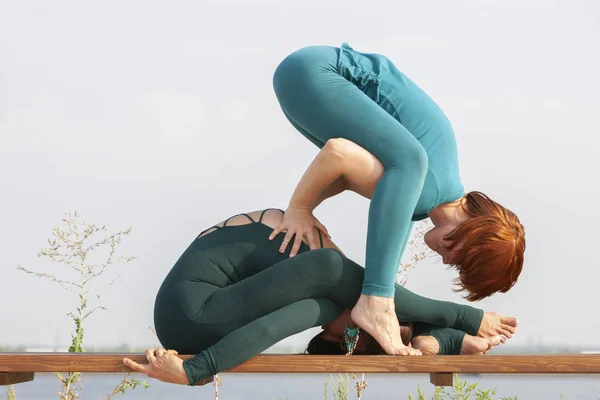 Mulheres bonitas exercitando ioga juntos sobre a natureza. Conceito de relacionamento, amor, verão, fim de semana, lua de mel, estilo de vida saudável . — Fotografia de Stock