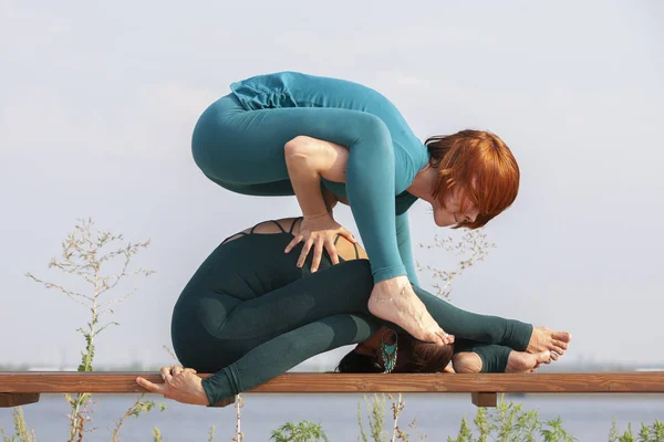 Schöne Frauen, die gemeinsam Yoga in der Natur praktizieren. Konzept der Beziehung, Liebe, Sommer, Wochenende, Flitterwochen, gesunder Lebensstil. — Stockfoto