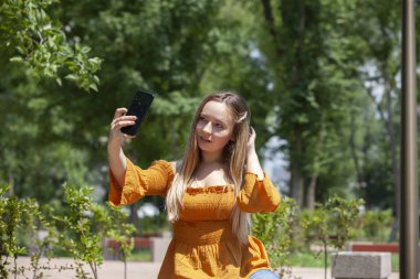 Gözlüklü göz kamaştırıcı kız telefonda konuşurken yakın yukarı portre. Açık portre bir sarışın genç kadın konuşurken onu Smartphone.