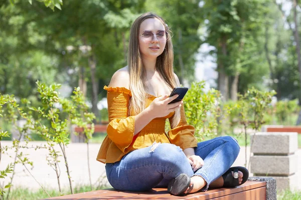 Nahaufnahme Porträt eines glamourösen Mädchens mit Brille, das am Telefon spricht. Außenporträt einer blonden jungen Frau, die mit ihrem Smartphone spricht. — Stockfoto