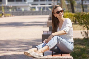 Parkta bankta oturan genç güzel kadın.