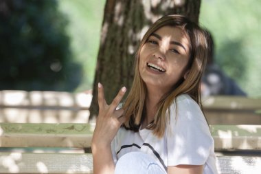 Kağıt bardaktan kahve içen genç kadın. Parkta bankta oturmak.