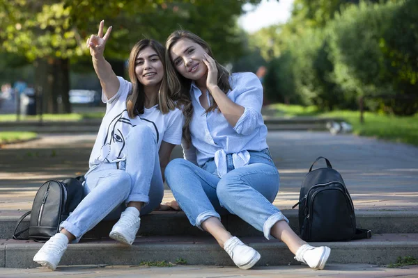 Dos hermosas chicas jóvenes están sentadas en las escaleras. Las novias están descansando en la ciudad en el verano . — Foto de Stock