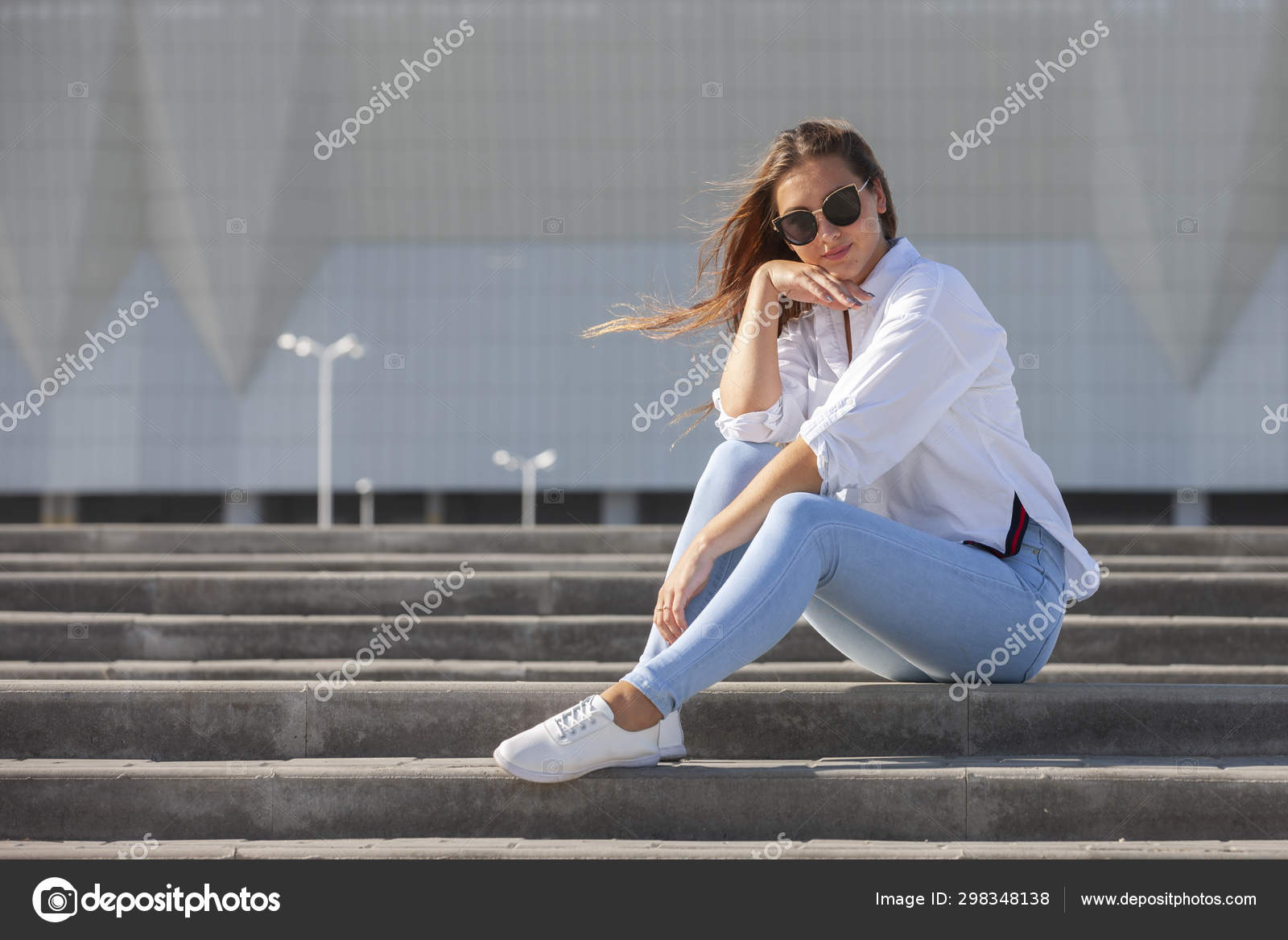 Young American Woman In A White T Shirt In Jeans In White Trendy Sneakers Relaxes Sitting On The Steps Cute European Girl Model Enjoys The Rest Spring Style Women S Clothing Stock Photo By C