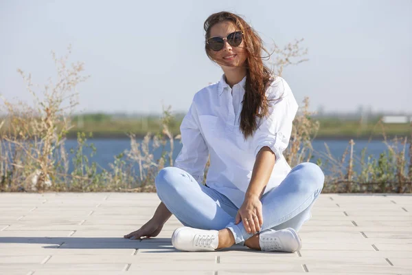 Mujer joven pensativa sentada en el suelo en el parque — Foto de Stock