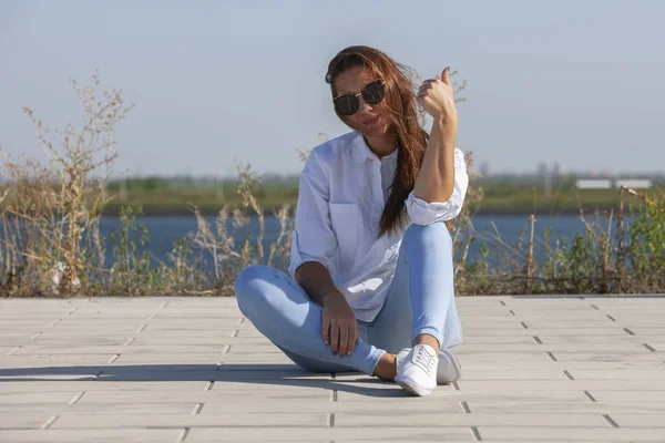 Doordachte jonge vrouw zittend op de grond in het park — Stockfoto