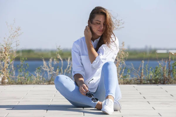 Задумчивая молодая женщина сидит на земле в парке — стоковое фото