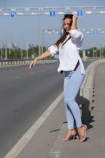 Mulher bonita carona caminhadas ao longo de uma estrada. — Fotografia de Stock