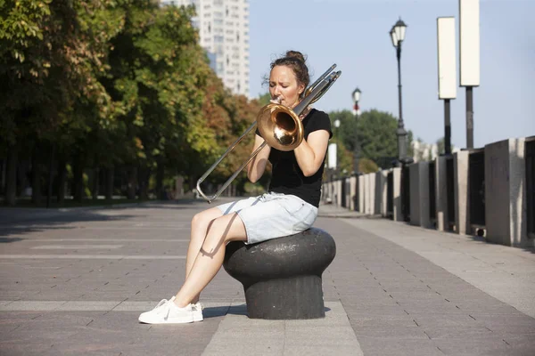 Dívka se učí hrát na trombon. Dívka hraje na promenádě. — Stock fotografie