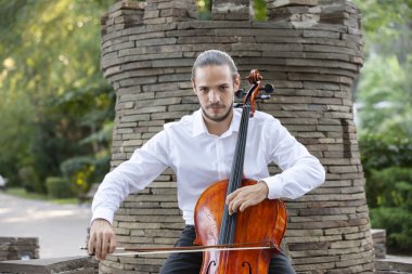 Genç adam dışarıda oynarken çello. Klasik müzik Çello çalan çellist