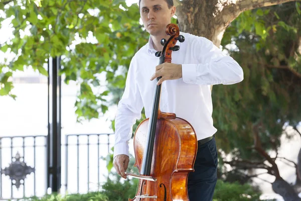 Street musician, young man playing cello in the street of big city, close up. — Stock Photo, Image