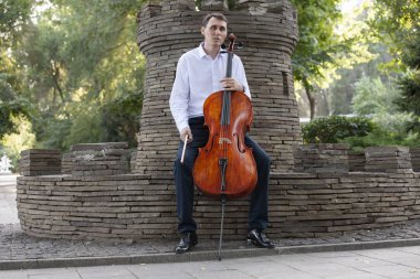 Genç adam dışarıda oynarken çello. Klasik müzik Çello çalan çellist