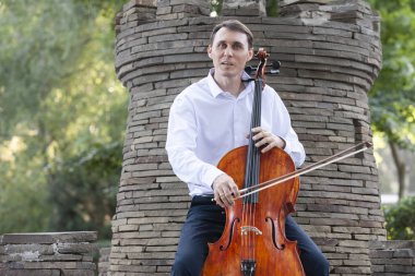 Genç adam dışarıda oynarken çello. Klasik müzik Çello çalan çellist