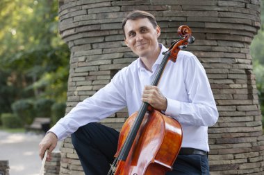 Genç adam dışarıda oynarken çello. Klasik müzik Çello çalan çellist