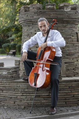 Genç adam dışarıda oynarken çello. Klasik müzik Çello çalan çellist