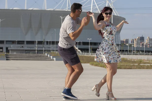 Casal jovem dançando dança latina contra paisagem urbana . — Fotografia de Stock