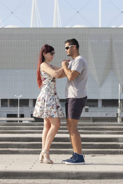 Young couple dancing Latino dance against urban landscape.