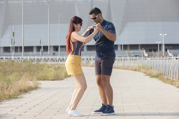 Casal jovem dançando dança latina contra paisagem urbana . — Fotografia de Stock