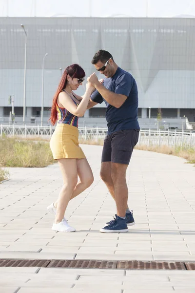 Young couple dancing Latino dance against urban landscape.