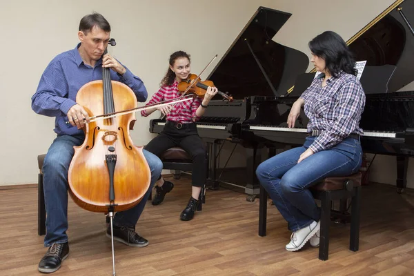 Un trio musicale di famiglia. Giovane violinista e violoncellista, il pianista li accompagna . — Foto Stock