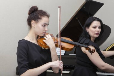 Senfoni orkestrasının müzisyenleri. Genç bir kemancı ve çellocu onlara eşlik eder..