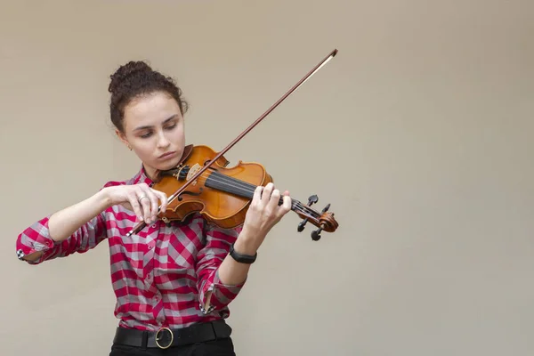 Ein Foto einer jungen Frau, die Geige spielt. Junge Geigerin bereitet sich auf Unterricht vor. — Stockfoto