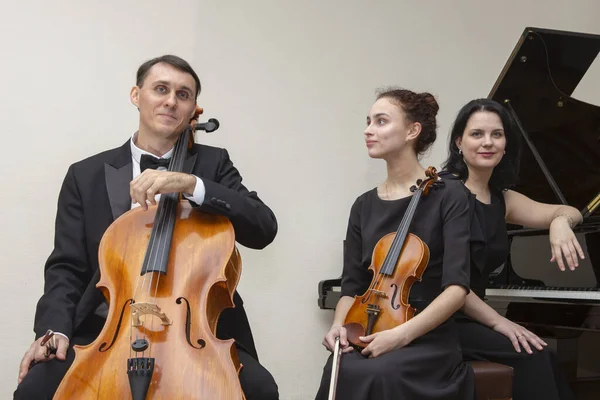 Symfoniorkesterns musiker. En ung violinist och cellist spelar, pianisten följer med dem. — Stockfoto