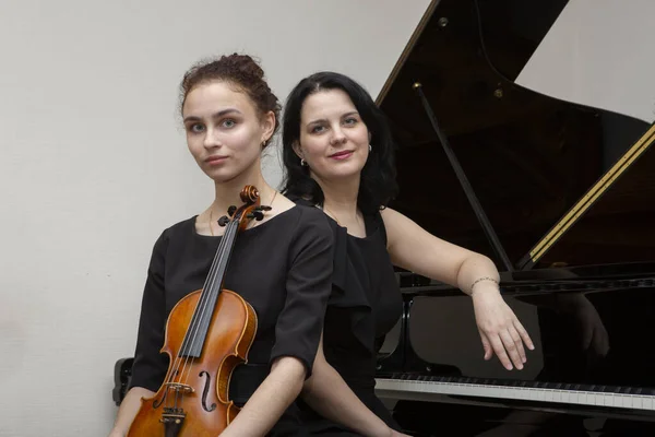 Symfoniorkesterns musiker. Ung violinist och pianist i konsertklänningar. — Stockfoto