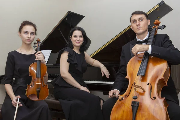 Un trio musicale di famiglia. Giovane violinista e violoncellista, il pianista li accompagna . — Foto Stock