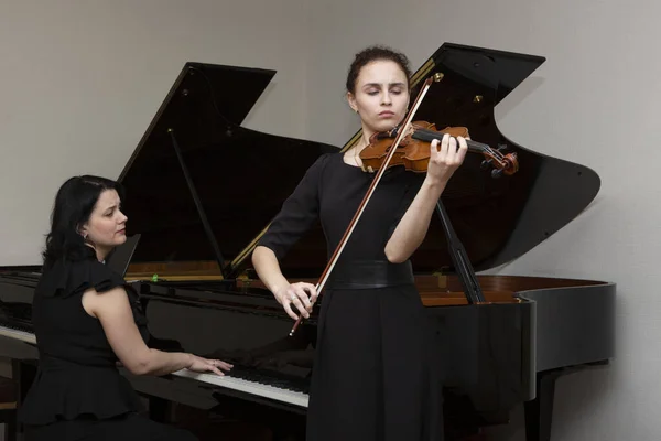 Senfoni orkestrasının müzisyenleri. Konser elbiseli genç kemancı ve piyanist.