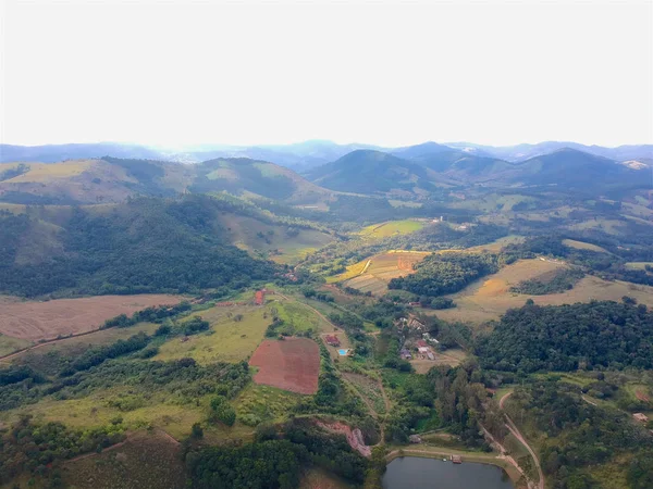 Aerial View of green nature scenic of forest in the mountain in tropical country. Aerial view of deforestation of a forest to make way for farm field and villa. Green area in the forest with lake