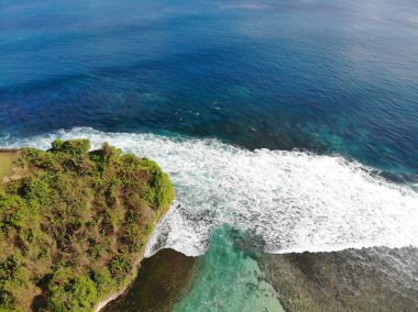 Kumlu sahil şeridi üzerinde hava görünümünü bir şaşırtıcı doğa manzara ile rock cliff. Güzel deniz suyu ile dalgalar Bali yaz sezonu sörf için. Güzellik Hint Okyanusu manzara, tatil beldesi