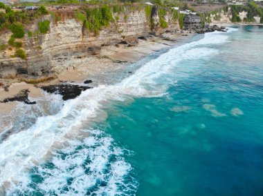 Kum kıyı şeridi mavi denizin kaya cliff ile havadan görünümü. Güzel turkuaz deniz suyu ile dalgalar Bali yaz sezonu sörf için. Güzellik Hint Okyanusu manzara, tatil beldesi