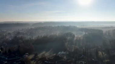 Orman ve tarım arazileri ile mavi gökyüzü güneş bakan sisli ve soğuk kış sabahı sırasında havadan görünümü. Belçika, Brabant Wallon.