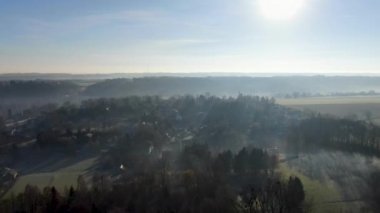 Orman ve tarım arazileri ile mavi gökyüzü güneş bakan sisli ve soğuk kış sabahı sırasında havadan görünümü. Belçika, Brabant Wallon.