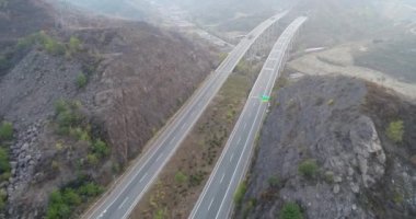 Kuru dağ yoluyla bridge ile yükseltilmiş Otoban hava görünümünü. Karayolu üzerinde otomobil ve kamyon her iki yönde sürüş ile dağ. Açık yol, otoyol kuru manzara içinde. Chengde, Çin.