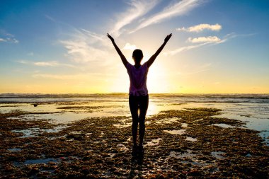 Gün batımında sahilde Yoga uygulamak sağlıklı kadın. Sahil günbatımında altında güçlü güven kadın. Kumsalda yoga yaparken genç kadın silüeti.